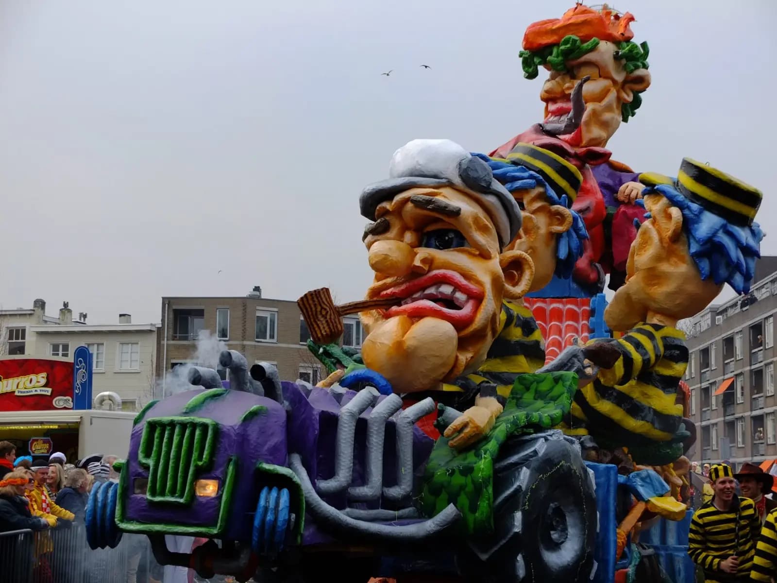 A float with a big painted man with a pipe in a car, in the parade of Kielegat in Breda