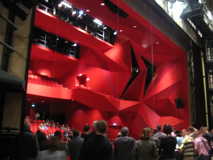 The warm-red Grote Zaal of AGORA Theater Lelystad, with rows of fixed seats facing the stage.
