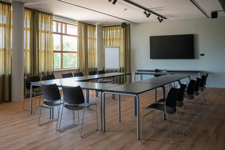 The empty Ambachtzaal Petit at C.C. Cascade, with its black chairs and dark-topped tables.