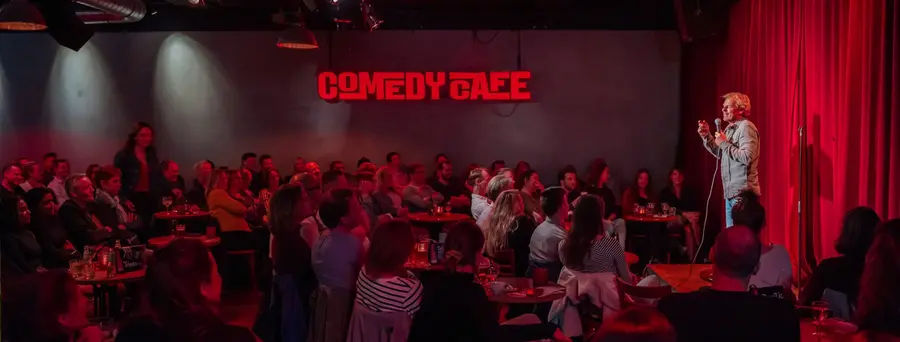 A comedian on stage at Comedy Café Amsterdam, with the audience in the room.