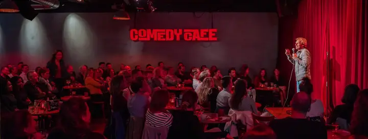 A comedian on stage at Comedy Café Amsterdam, with the audience in the room.
