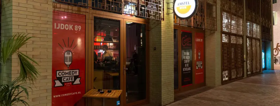 The exterior of Comedy Café Amsterdam on IJdok, with the club entrance and waterfront.