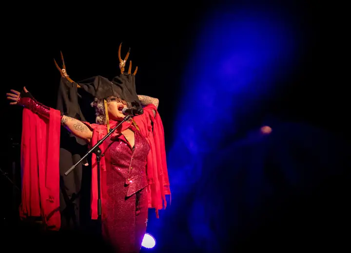 The stage of Theater De Storm during a live show, with a drum kit, amplifiers and blue and red stage lights.