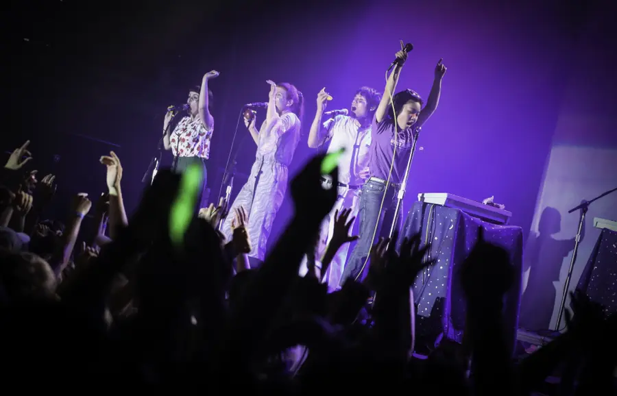 A band on the First Avenue stage under purple light with the crowd's raised hands in the foreground
