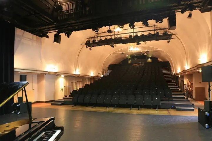 The empty Grote Zaal of Het Posttheater with its raked telescopic stand and wooden stage.