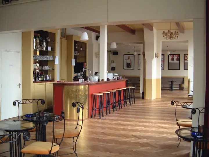The foyer of Het Posttheater with its bar, bistro tables and theatre posters on the walls.