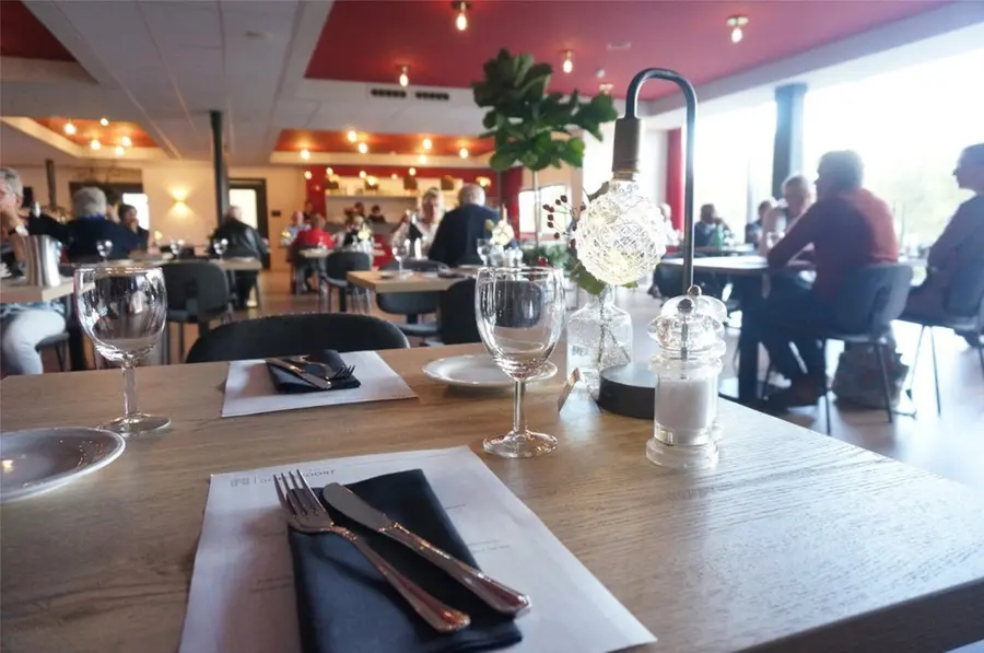 The theatre restaurant at Stadsschouwburg Middelburg, with set tables and guests dining by the windows.