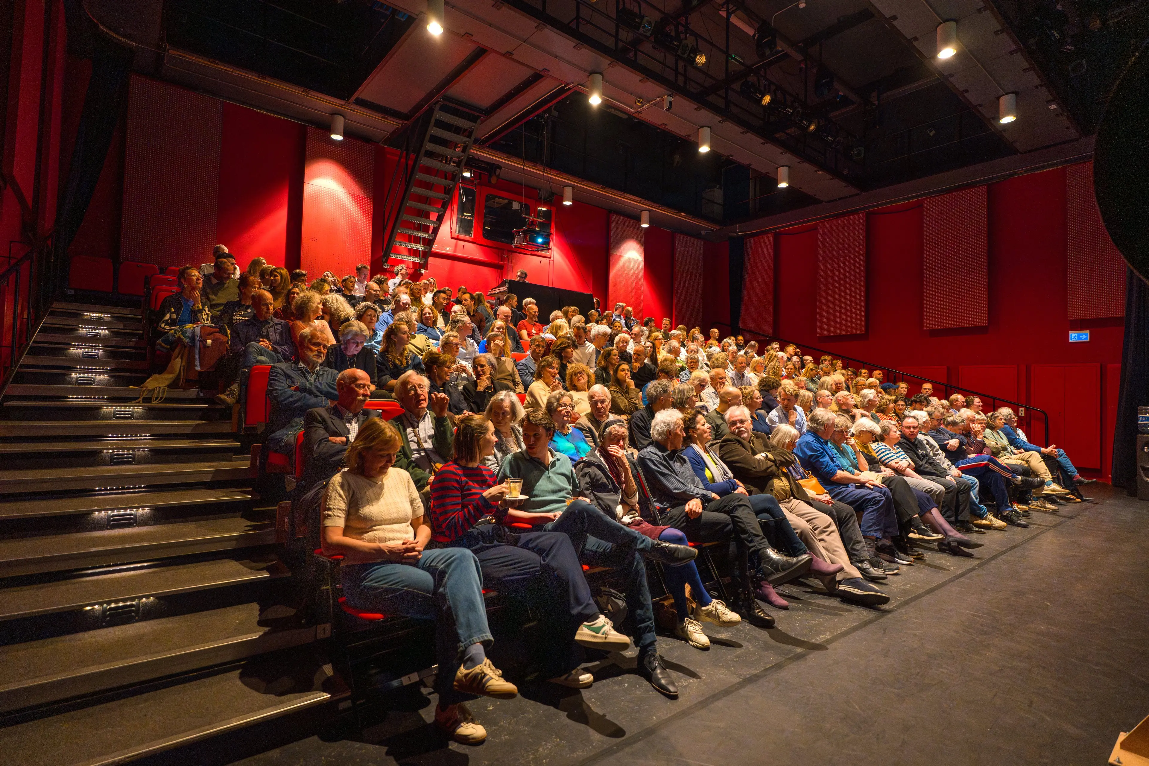 The empty flat-floor theatre hall of Theater De Landing on Campus Uilenstede, with numbered rows of seats facing the stage.