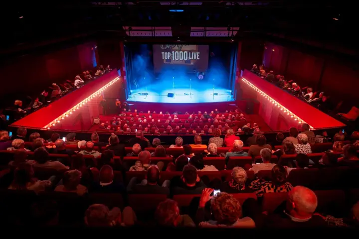 The empty Theatre Hall at Theater 't Voorhuys, with its fixed rows of seats, balcony and stage.
