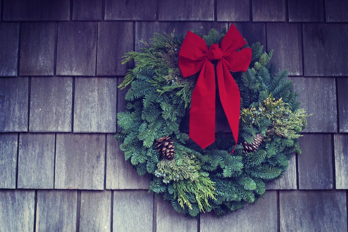 A fir Christmas wreath with a red bow on a wooden wall